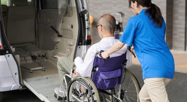 a disability support worker pushing a man in a wheelchair into a van
