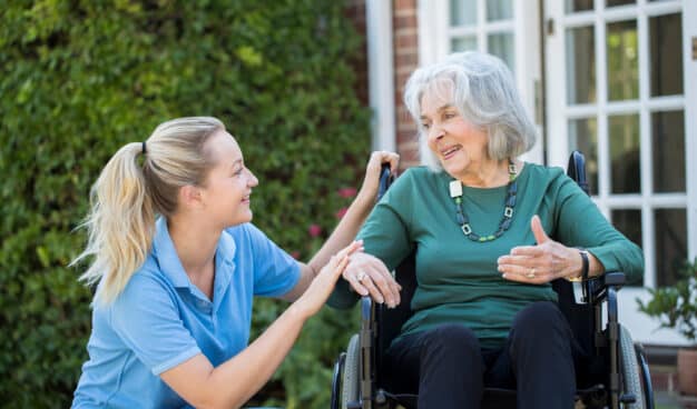 a disability support worker caring for an elderly woman in a wheelchair
